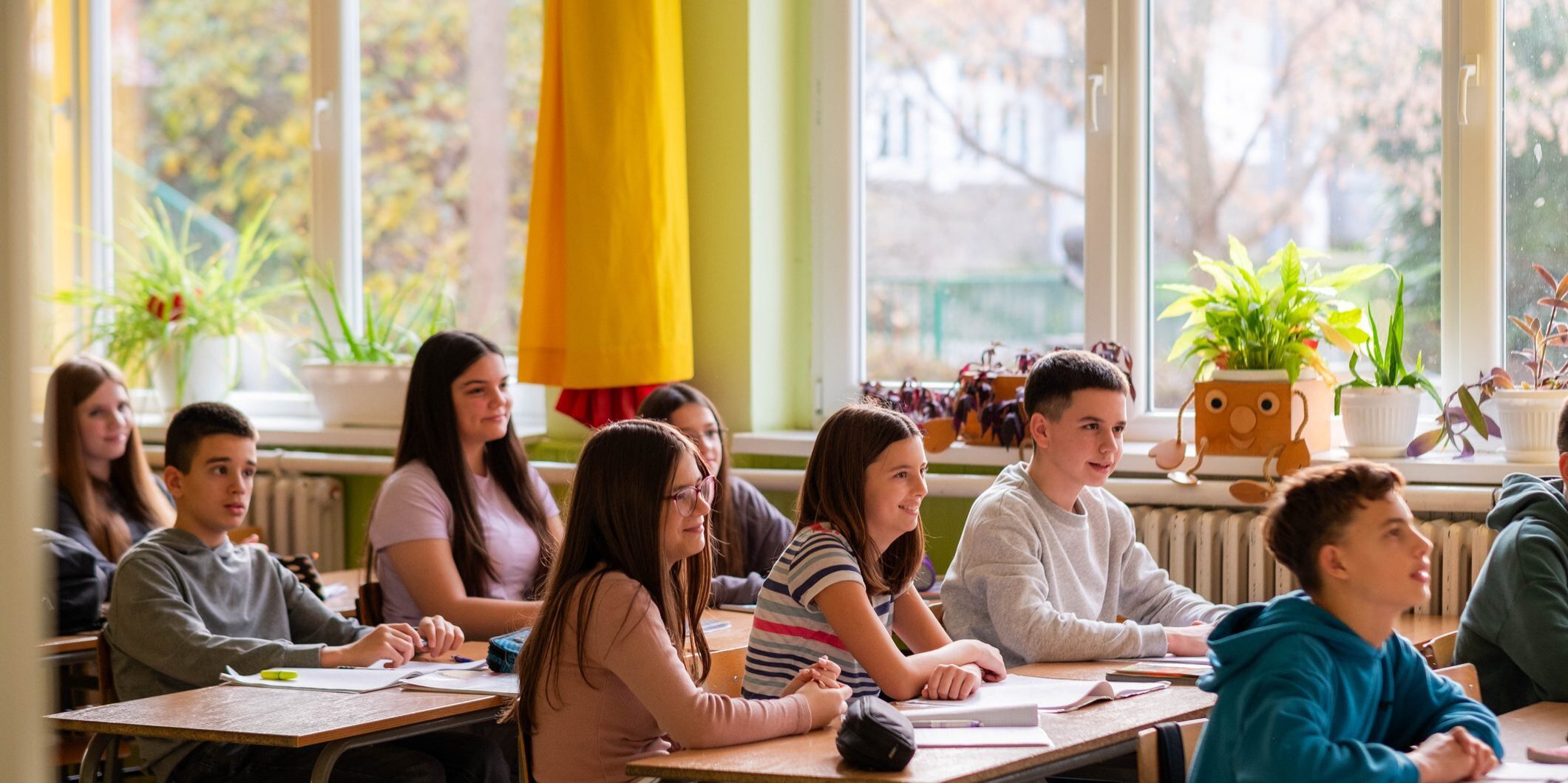 Group of teenage kids sitting in the classroom during tha class and listening teacher